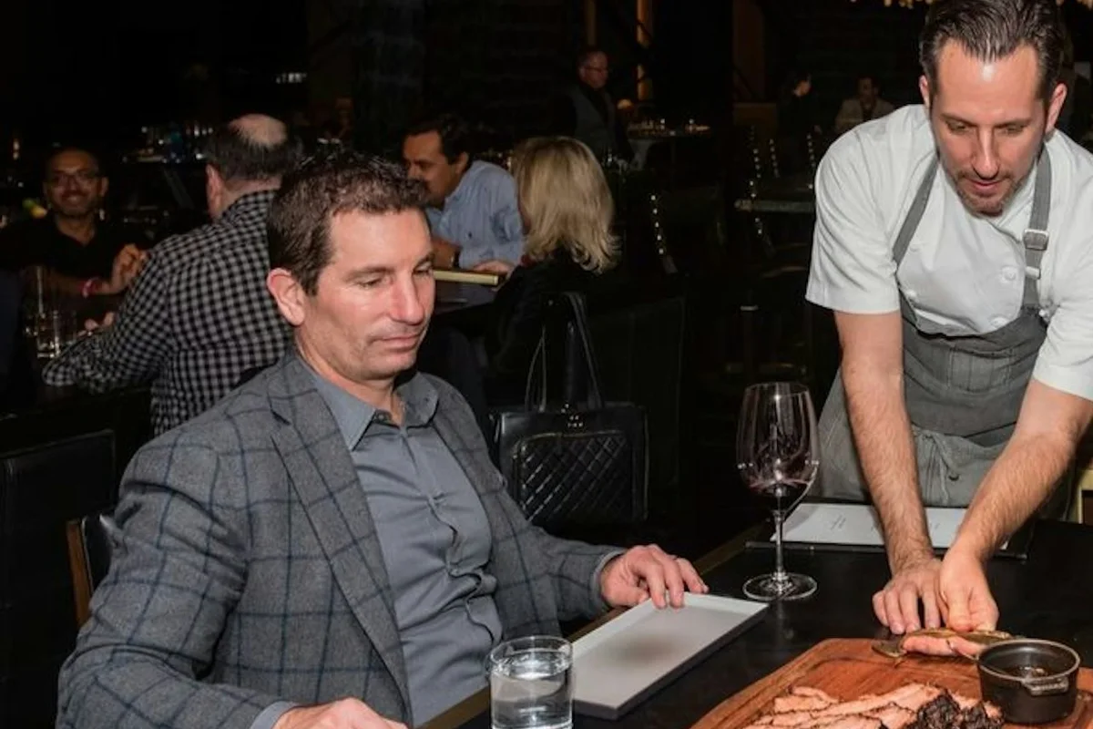 A diner watching steak being carved at a restaurant table